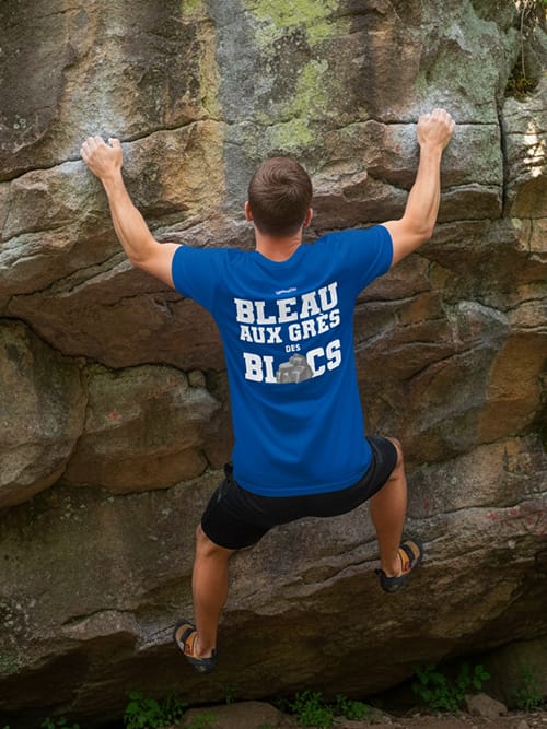 Homme escaladant une paroi rocheuse avec le T-shirt bleu Bleau aux Grès des Blocs 