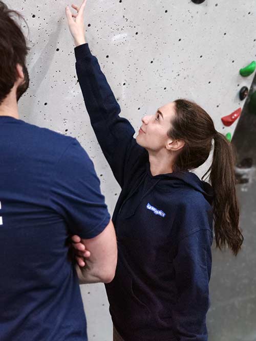 Femme de profil dans une salle de bloc portant le sweat à capuche bleu marine Grimpeur de blocs, maître des hauteurs