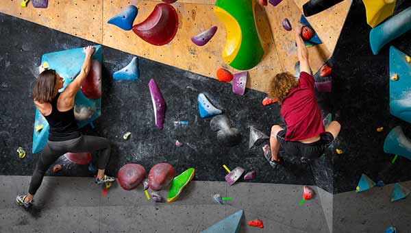 Homme et femme grimpant sur un mur de bloc
