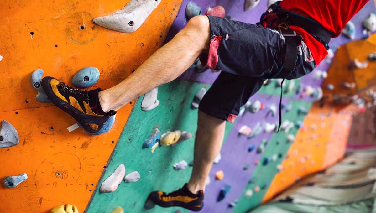 Homme grimpant un mur de bloc