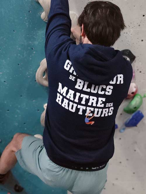 Homme de dos en train de grimper sur un mur de bloc avec le sweat à capuche bleu marine Grimpeur de blocs, maître des hauteurs