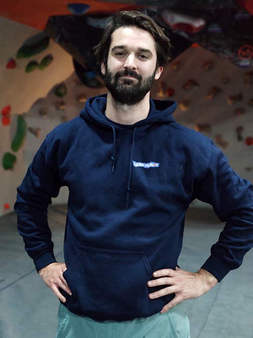 Homme de face dans une salle de bloc portant le sweat à capuche bleu marine Roi du bloc
