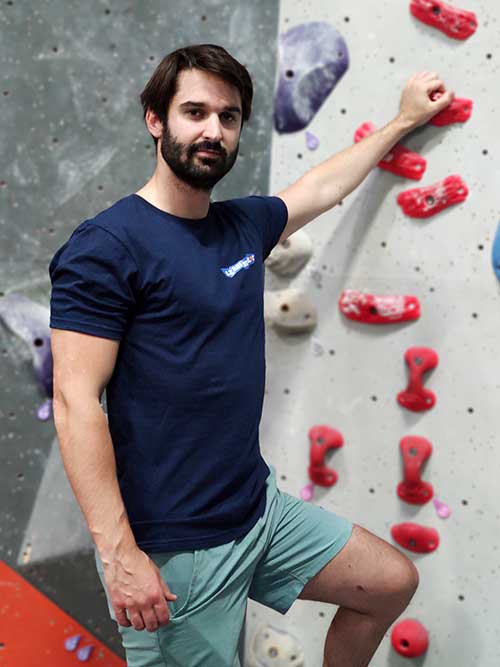 Homme de face dans une salle de bloc portant le t-shirt bleu marine Je suis le maître du bloc
