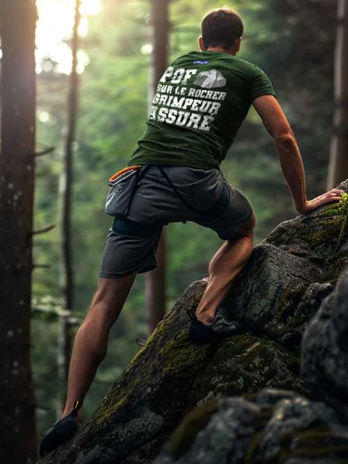 Homme de dos grimpant un rocher en forêt de Fontainebleau, portant le t-shirt vert forêt Pof sur le Rocher, Grimpeur Assuré