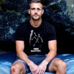Grimpeur blessé assis sur un crashpad, portant le t-shirt Tombe dignement