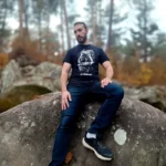 T-shirt Je lâche pas porté par Thibault assis sur un rocher en forêt