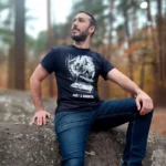 T-shirt Prêt à grimper porté par Thibault assis sur un rocher en forêt