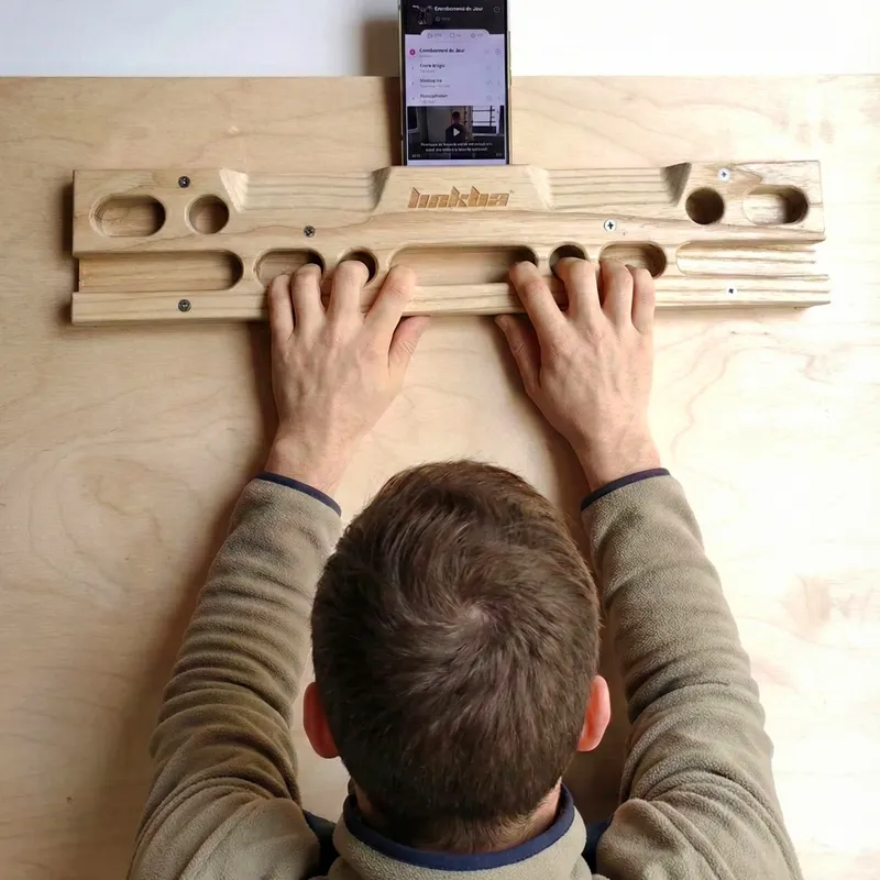 Grimpeur s’entraînant sur une poutre d’escalade en bois pour renforcer les doigts à la maison